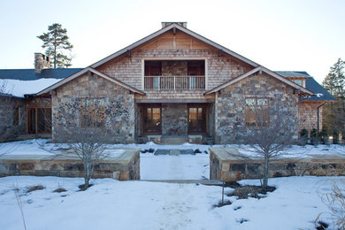 Rustic brown two-story stone exterior home idea in Other
