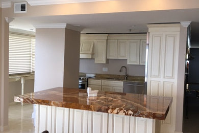 Foto di un cucina con isola centrale minimal con ante con bugna sagomata, top in granito, elettrodomestici in acciaio inossidabile e pavimento in marmo