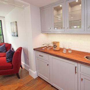 ボストンの小さいトランジショナルスタイルのおしゃれなウェットバー (茶色い床、ドロップインシンク、シェーカースタイル扉のキャビネット、グレーのキャビネット、木材カウンター、白いキッチンパネル、サブウェイタイルのキッチンパネル、濃色無垢フローリング) の写真