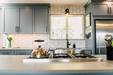 シアトルにある高級な小さなエクレクティックスタイルのおしゃれなキッチン (エプロンフロントシンク、シェーカースタイル扉のキャビネット、青いキャビネット、クオーツストーンカウンター、白いキッチンパネル、セラミックタイルのキッチンパネル、シルバーの調理設備、竹フローリング、茶色い床、グレーのキッチンカウンター) の写真