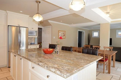 Open concept kitchen - mid-sized traditional l-shaped travertine floor and beige floor open concept kitchen idea in Montreal with shaker cabinets, white cabinets, granite countertops, an island, beige backsplash, stone tile backsplash and stainless steel appliances