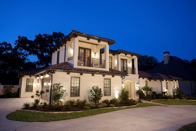This is an example of a large mediterranean two-storey stucco beige exterior in Austin with a gambrel roof.