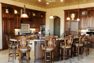 Inspiration for a large rustic l-shaped ceramic tile eat-in kitchen remodel in Salt Lake City with a drop-in sink, raised-panel cabinets, dark wood cabinets, granite countertops, beige backsplash, ceramic backsplash, stainless steel appliances and two islands