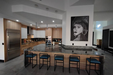 ラスベガスにある高級な広いモダンスタイルのおしゃれなアイランドキッチン (フラットパネル扉のキャビネット、ベージュのキャビネット、シルバーの調理設備) の写真