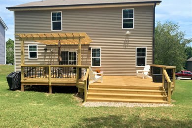 Large transitional backyard ground level mixed material railing deck photo in Raleigh with a pergola