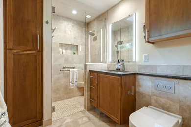 Design ideas for a small traditional master bathroom in Portland with raised-panel cabinets, medium wood cabinets, a curbless shower, a wall-mount toilet, beige tile, travertine, beige walls, travertine floors, an undermount sink, engineered quartz benchtops, multi-coloured floor and a hinged shower door.