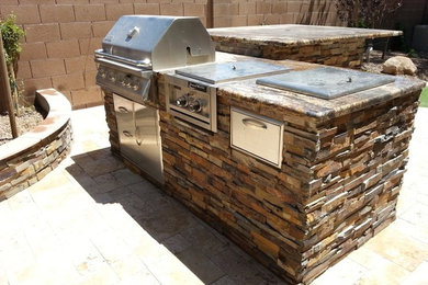 Example of a mid-sized backyard stone patio kitchen design in Phoenix with no cover