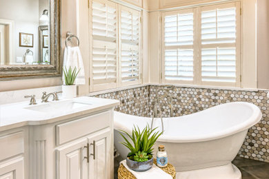 Example of a mid-sized transitional master beige tile and porcelain tile porcelain tile and gray floor bathroom design in Other with raised-panel cabinets, white cabinets, a one-piece toilet, beige walls, an undermount sink, quartzite countertops, a hinged shower door and white countertops