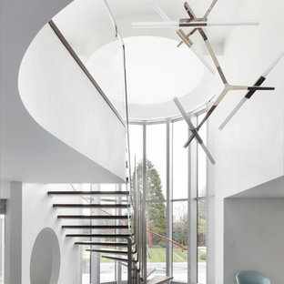 This is an example of an expansive contemporary wood curved staircase in London with open risers.