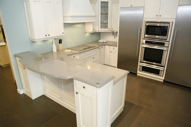 Inspiration for a mid-sized transitional u-shaped concrete floor and brown floor kitchen remodel in Orange County with shaker cabinets, white cabinets, stainless steel appliances and a peninsula