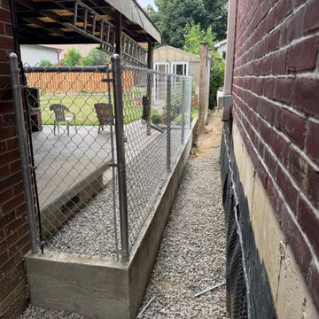 Galvanized chain link fence set on a poured concrete base in a Mississauga side
