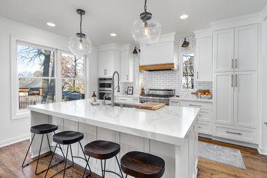 Example of a mid-sized transitional galley medium tone wood floor and brown floor kitchen design in Other with an undermount sink, shaker cabinets, white cabinets, white backsplash, subway tile backsplash, paneled appliances, an island and white countertops