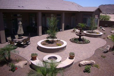Mid-sized backyard brick patio photo in Phoenix with a fire pit and a roof extension