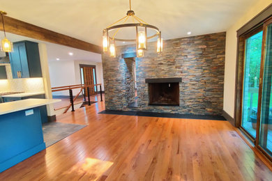 Inspiration for a large rustic medium tone wood floor, orange floor and exposed beam living room remodel in Bridgeport with white walls, a two-sided fireplace and a stacked stone fireplace