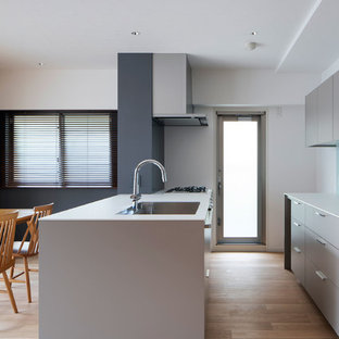 Выдающиеся фото от архитекторов и дизайнеров интерьера: маленькая параллельная кухня-гостиная в современном стиле с накладной раковиной, фасадами с декоративным кантом, серыми фасадами, столешницей из ламината, белым фартуком, фартуком из стеклянной плитки, полом из фанеры, островом, бежевым полом и белой столешницей