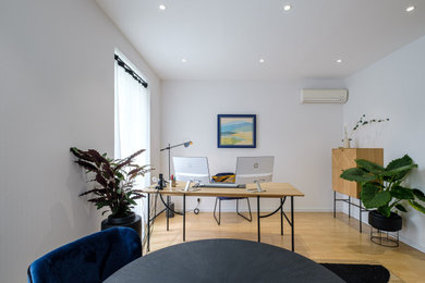 Diseño de despacho actual de tamaño medio sin chimenea con paredes blancas, suelo laminado, escritorio independiente, suelo beige y papel pintado