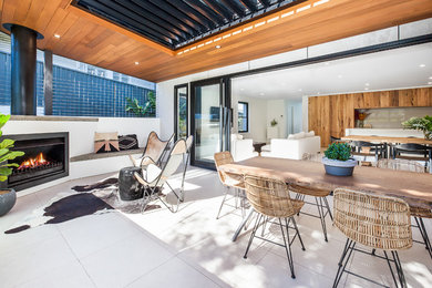 This is an example of a contemporary backyard deck in Sydney with with fireplace and a roof extension.