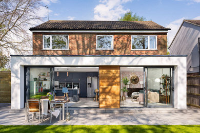 This is an example of a white contemporary render house exterior in Hampshire with board and batten cladding.