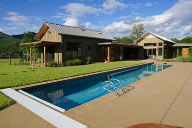 Ejemplo de piscina alargada campestre de tamaño medio rectangular en patio trasero con paisajismo de piscina