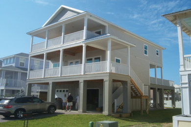 Large beach style beige three-story wood exterior home photo in Orlando with a metal roof