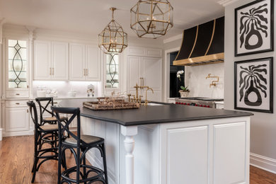 Example of a large transitional l-shaped medium tone wood floor and brown floor eat-in kitchen design in St Louis with raised-panel cabinets, white cabinets, quartz countertops, white backsplash, quartz backsplash, stainless steel appliances, an island and black countertops