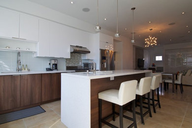 Large trendy galley ceramic tile eat-in kitchen photo in Orange County with a drop-in sink, flat-panel cabinets, white cabinets, quartz countertops, blue backsplash, glass tile backsplash, stainless steel appliances and an island