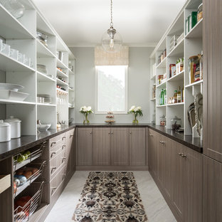 This is an example of a large transitional u-shaped kitchen pantry in Grand Rapids with brown cabinets, marble benchtops, blue splashback, stainless steel appliances and ceramic floors.