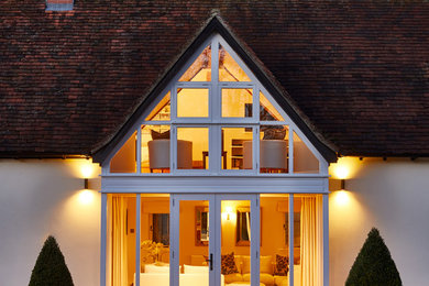 На фото: двухэтажный, белый частный загородный дом в стиле кантри с облицовкой из крашеного кирпича, вальмовой крышей, черепичной крышей и красной крышей