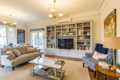 This is an example of a mid-sized traditional open concept living room in Melbourne with white walls, medium hardwood floors, no fireplace and a built-in media wall.