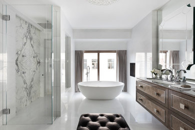 This is an example of a large contemporary master bathroom in London with brown cabinets, a freestanding tub, an open shower, a one-piece toilet, white walls, marble floors, a drop-in sink and marble benchtops.