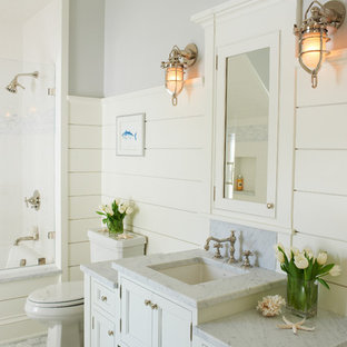 Example of a coastal bathroom design in New York with recessed-panel cabinets, white cabinets, white walls and an undermount sink