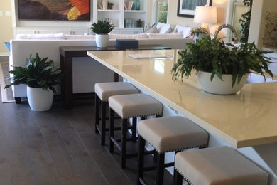 Trendy l-shaped brown floor kitchen photo in Other with white cabinets and an island