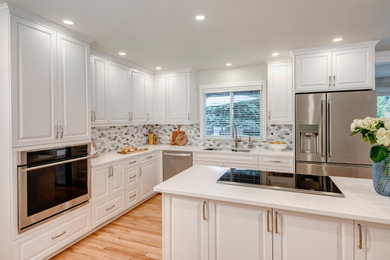 Kitchen - mid-sized transitional light wood floor kitchen idea in Seattle with an undermount sink, raised-panel cabinets, white cabinets, quartz countertops, gray backsplash, marble backsplash, stainless steel appliances, an island and white countertops