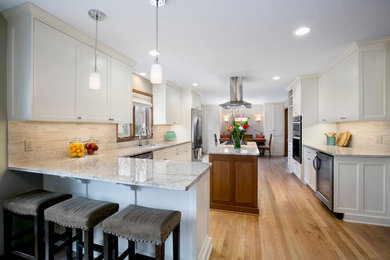 Large transitional u-shaped eat-in kitchen in Minneapolis with an undermount sink, shaker cabinets, white cabinets, quartzite benchtops, beige splashback, matchstick tile splashback, stainless steel appliances, medium hardwood floors, with island and brown floor.