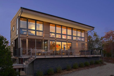 Example of a large minimalist beige two-story wood exterior home design in New York with a metal roof