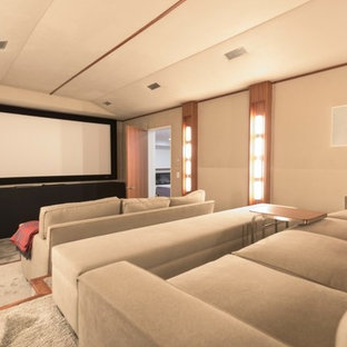 Photo of a large contemporary enclosed home cinema in Toronto with beige walls, carpet, a projector screen and grey floors.