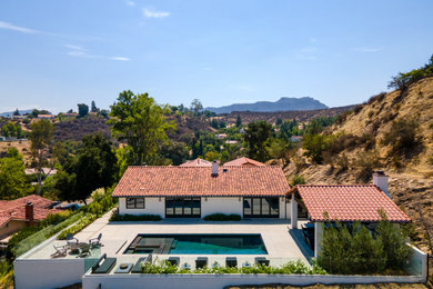 Huge minimalist white one-story stucco house exterior photo in Los Angeles with a red roof