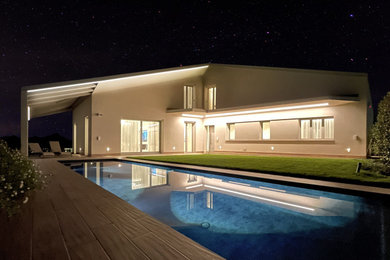 Foto di una grande piscina a sfioro infinito minimal rettangolare davanti casa con paesaggistica bordo piscina e pavimentazioni in mattoni