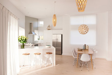 Small scandinavian u-shaped eat-in kitchen in Auckland with a single-bowl sink, flat-panel cabinets, white cabinets, quartz benchtops, white splashback, glass sheet splashback, stainless steel appliances, light hardwood floors and with island.