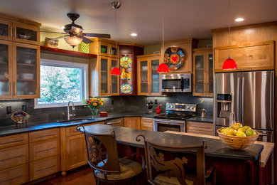 Example of a large transitional l-shaped terra-cotta tile eat-in kitchen design in Phoenix with an undermount sink, shaker cabinets, medium tone wood cabinets, solid surface countertops, black backsplash, stainless steel appliances and an island