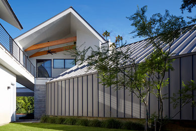 Photo of a large contemporary two-storey grey exterior in Austin with mixed siding and a gambrel roof.