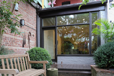 Example of a trendy galley medium tone wood floor and multicolored floor eat-in kitchen design in Baltimore with flat-panel cabinets, granite countertops, white backsplash, brick backsplash, stainless steel appliances and an island