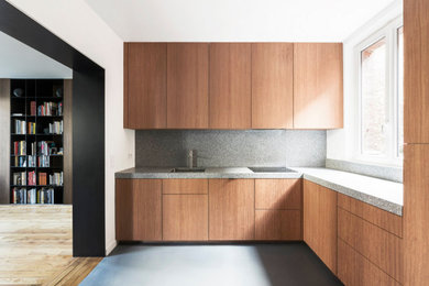 Idée de décoration pour une cuisine design fermée avec un évier intégré, un placard à porte affleurante, des portes de placard rouges, un plan de travail en terrazzo, une crédence grise, un électroménager en acier inoxydable, sol en béton ciré, un sol gris et un plan de travail gris.