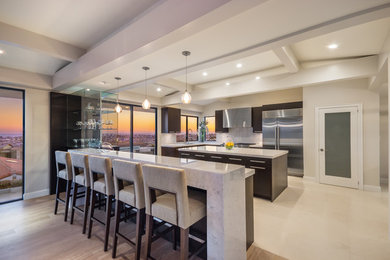 Inspiration for a mid-sized contemporary u-shaped limestone floor and beige floor eat-in kitchen remodel in Orange County with an undermount sink, flat-panel cabinets, dark wood cabinets, marble countertops, white backsplash, stone slab backsplash, stainless steel appliances, two islands and gray countertops