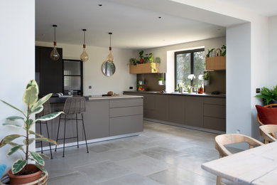 Large contemporary l-shaped open plan kitchen in Sussex with flat-panel cabinets, grey cabinets and an island.