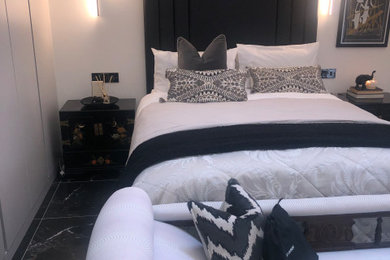 Inspiration for a large contemporary master and cream and black bedroom in Other with white walls, porcelain flooring, black floors, a vaulted ceiling and feature lighting.