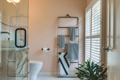 他の地域にある高級な小さなモダンスタイルのおしゃれな浴室 (フラットパネル扉のキャビネット、淡色木目調キャビネット、コーナー設置型シャワー、一体型トイレ	、白いタイル、セラミックタイル、ピンクの壁、セラミックタイルの床、ベッセル式洗面器、クオーツストーンの洗面台、白い床、開き戸のシャワー、マルチカラーの洗面カウンター、洗面台1つ、フローティング洗面台) の写真