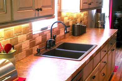 Elegant single-wall medium tone wood floor eat-in kitchen photo in Austin with a double-bowl sink, raised-panel cabinets, distressed cabinets, laminate countertops, multicolored backsplash, stone tile backsplash, stainless steel appliances and an island