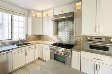 Kitchen pantry - large modern u-shaped vinyl floor, white floor and tray ceiling kitchen pantry idea in San Diego with an undermount sink, shaker cabinets, white cabinets, quartzite countertops, green backsplash, glass tile backsplash, stainless steel appliances, an island and gray countertops