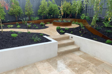 Small backyard partial sun garden in Melbourne with a garden path, natural stone pavers and a wood fence for spring.